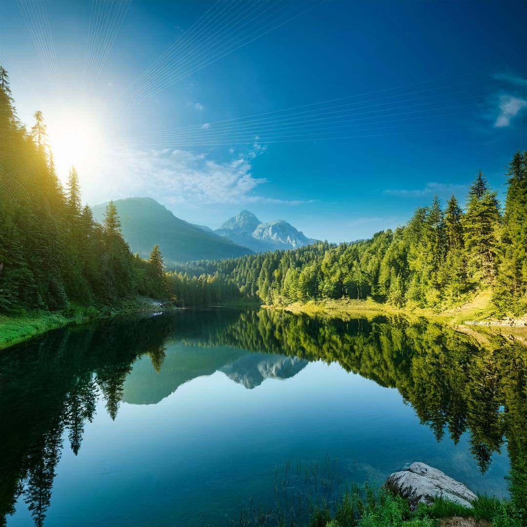 Lake with trees around the banks of the crystal blue water - sun shining in the background - peaceful setting